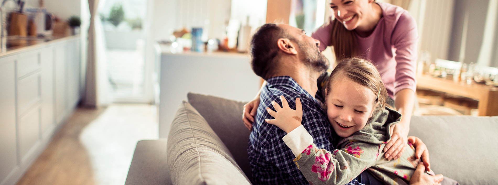 A family of four embracing in a warm, homey setting.