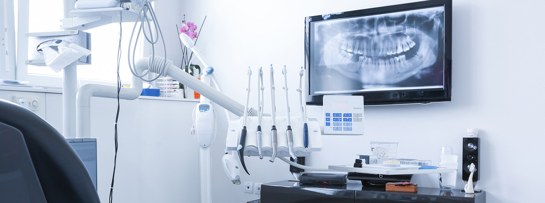 The image shows a modern dental clinic interior with various pieces of equipment, including a dental chair and an X-ray machine.