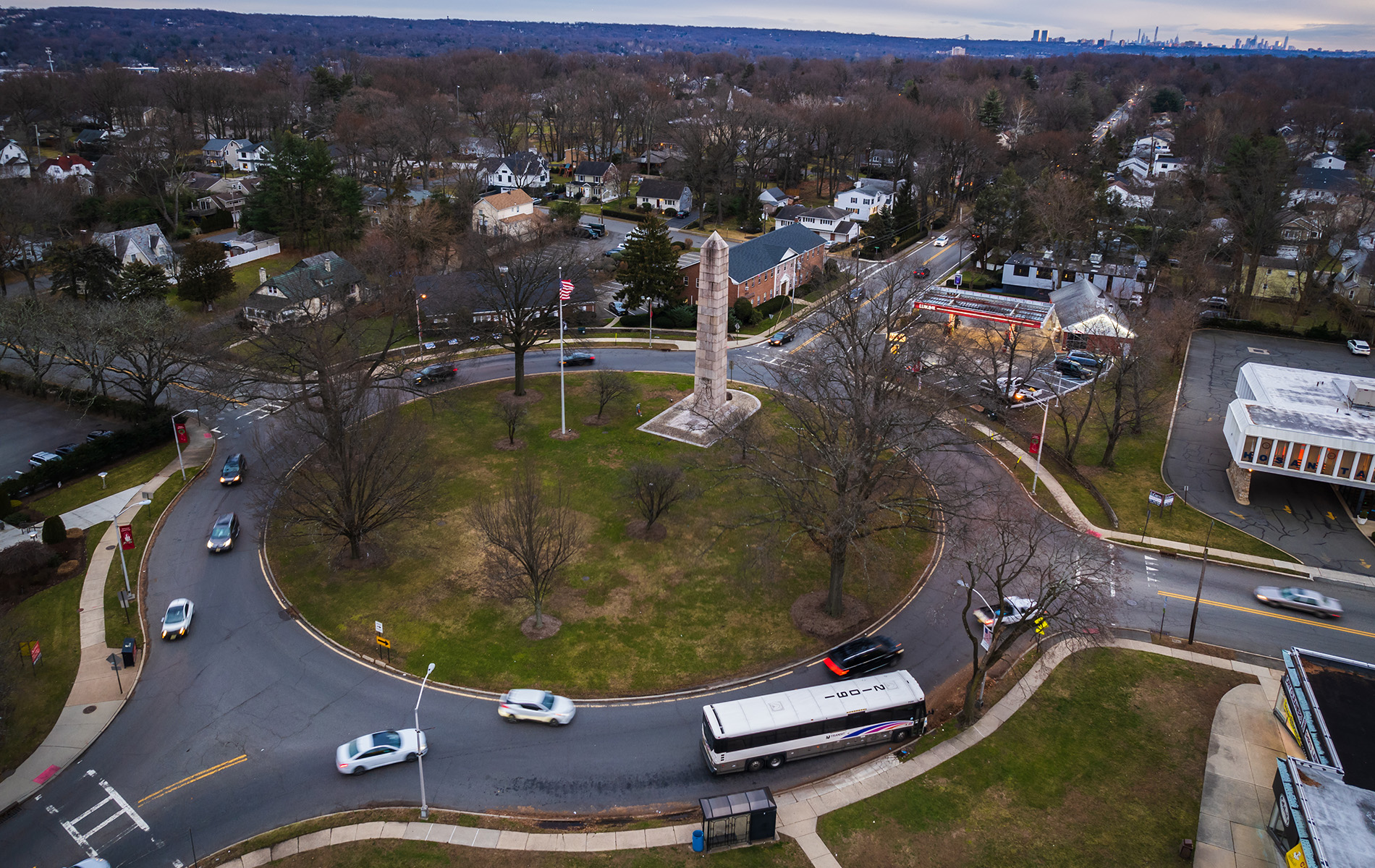 Aerial view of a town square with a roundabout, surrounded by streets and buildings.