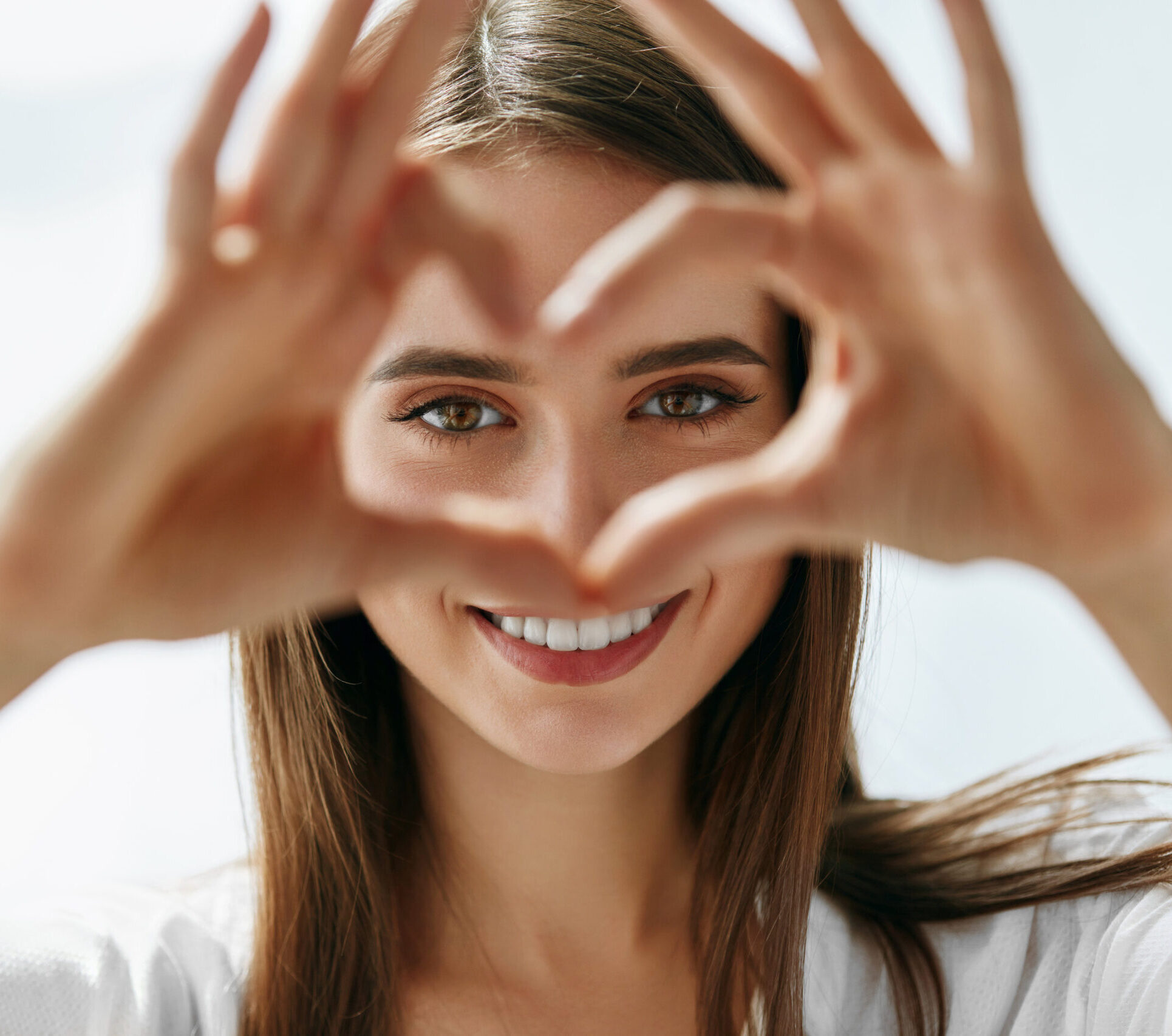 Healthy Eyes And Vision. Portrait Of Beautiful Happy Woman Holding Heart Shaped Hands Near Eyes. Closeup Of Smiling Girl With Healthy Skin Showing Love Sign. Eyecare. High Resolution Image